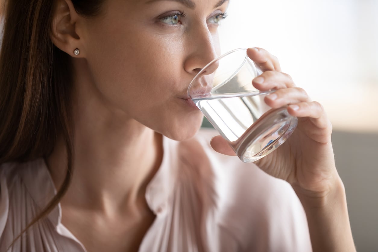 Kvinne som drikker kaldt vann fra et glass