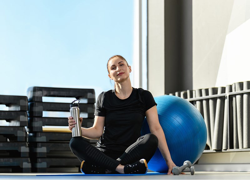 Kvinne på treningsstudio holder en vannflaske